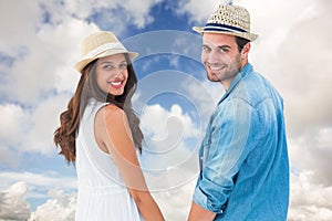 Composite image of happy hipster couple holding hands and smiling at camera