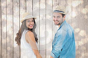 Composite image of happy hipster couple holding hands and smiling at camera