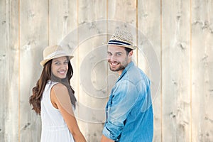 Composite image of happy hipster couple holding hands and smiling at camera