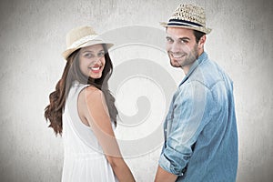 Composite image of happy hipster couple holding hands and smiling at camera