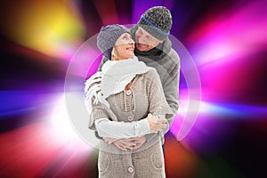 Composite image of happy mature couple in winter clothes embracing