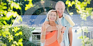 Composite image of happy older couple holding paint roller