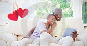 Composite image of happy smiling couple using laptop on couch