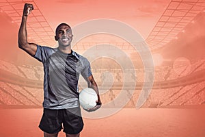Composite image of happy sportsman with clenched fist holding rugby ball