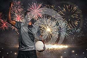 Composite image of happy sportsman with clenched fist holding rugby ball