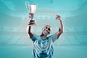 Composite image of happy sportsman looking up and cheering while holding trophy