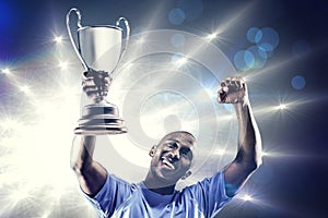 Composite image of happy sportsman looking up and cheering while holding trophy