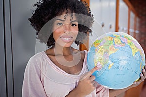 Composite image of happy woman pointing to globe