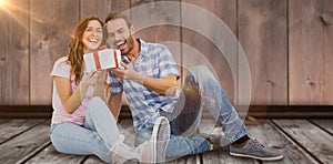 Composite image of happy young couple holding gift