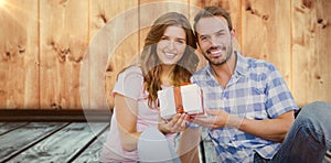 Composite image of happy young couple holding gift