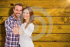 Composite image of happy young couple putting thumbs up