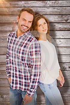 Composite image of happy young couple standing back to back