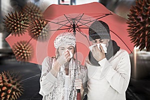 Composite image of ill couple sneezing in tissue while standing under umbrella