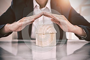 Composite image of insurer protecting a house by his hands