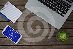 Composite image of laptop, pot plant, notepad, pen and mobile phone on wooden plank