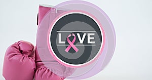 Composite image of love text with breast cancer awareness ribbon and boxing gloves at table