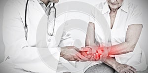 Composite image of male physiotherapist examining a senior womans wrist