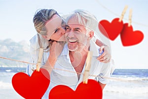 Composite image of man giving his smiling wife a piggy back at the beach