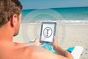 Composite image of man using digital tablet on deck chair at the beach