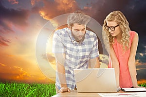 Composite image of man using laptop while discussing with woman at desk