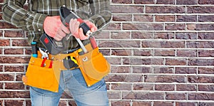 Composite image of manual worker holding gloves and hammer power drill