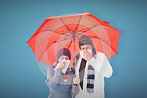 Composite image of mature couple blowing their noses under umbrella