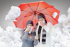 Composite image of mature couple blowing their noses under umbrella