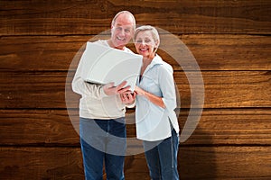 Composite image of mature couple smiling at camera with laptop