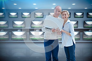 Composite image of mature couple smiling at camera with laptop