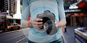 Composite image of mid section of female photographer holding digital camera