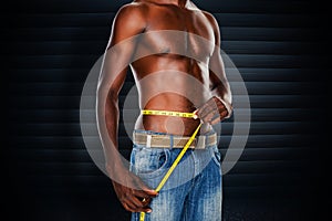 Composite image of mid section of a fit shirtless man measuring waist