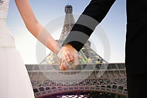Composite image of mid section of newlywed couple holding hands in park