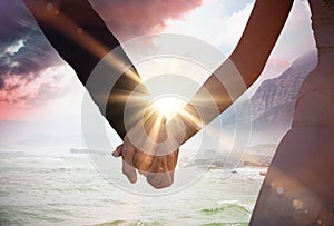 Composite image of mid section of newlywed couple holding hands in park