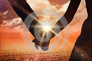Composite image of mid section of newlywed couple holding hands in park
