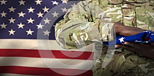 Composite image of mid section of soldier holding american flag