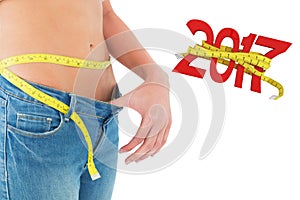 Composite image of mid section of woman measuring waist in a big sized jeans