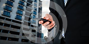 Composite image of midsection of businessman text messaging on mobile phone