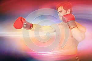 Composite image of muscly man wearing red boxing gloves and punching