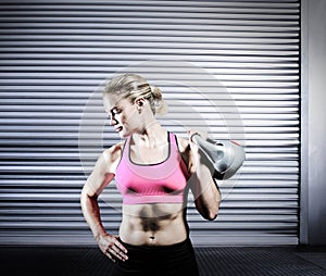 Composite image of muscular woman lifting heavy kettlebell