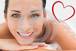 Composite image of peaceful brunette lying with salt scrub on back smiling at camera