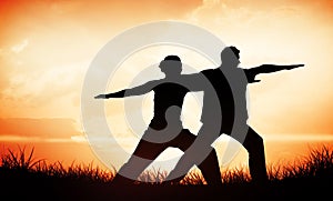 Composite image of peaceful couple in white doing yoga together in warrior position