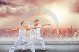 Composite image of peaceful couple in white doing yoga together in warrior position