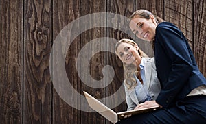 Composite image of portrait of business women posing with laptop