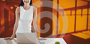 Composite image of portrait of businesswoman with laptop standing at table