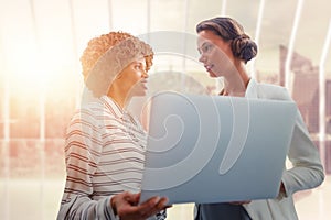 Composite image of portrait of businesswomen posing with laptop