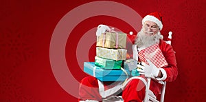 Composite image of portrait of cheerful santa claus holding christmas presents on chair