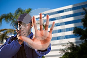 Composite image of portrait of confident security talking on walkie talkie and making stop gesture