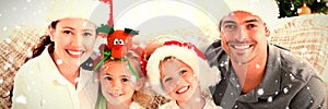 Composite image of portrait of a happy family with christmas hats sitting on the sofa