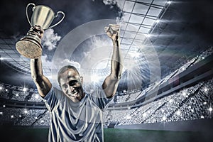 Composite image of portrait of happy sportsman cheering while holding trophy