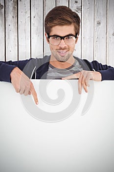 Composite image of portrait of man wearing eyeglasses pointing on billboard